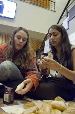 (From left) Heather Rounds, a junior magazine, middle eastern studies and citizenship and civic engagement triple major, and Ella Mendonsa, a senior political science and public policy dual major, help make peanut butter and jelly sandwiches to share with fellow DAT Rally protesters during a staged sit-in in the Crouse-Hinds Hall lobby.