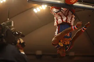 Bull hangs upside down on the rim after completing a thunderous dunk.
