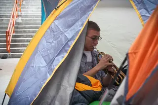 Kevin Del Fuoco, a freshman music performance major, plays trumpet inside his tent next to Gate D of the Carrier Dome.