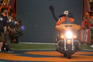 Otto the Orange enters the field on a motorcycle.