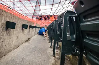 A young fan reaches under the orange barrier meant to keep fans 6 feet apart to grab a ball that had fallen under the seats.
